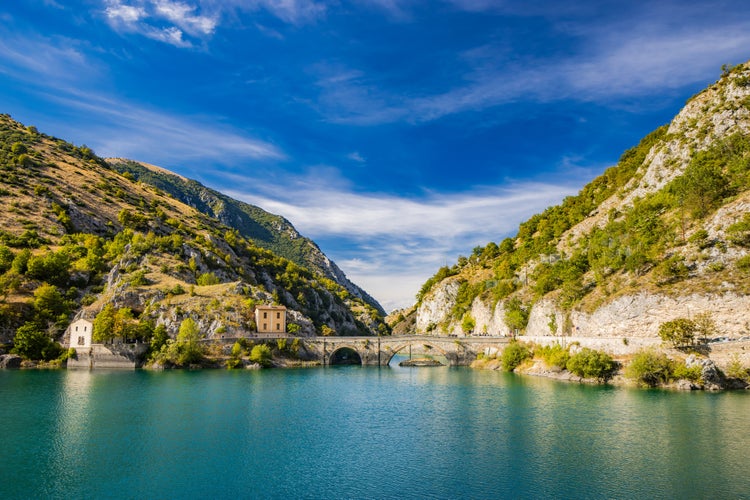 Lake San Domenico, in the Sagittario Gorges, in Abruzzo, L'Aquila, Italy. The small hermitage with the stone bridge. The turquoise color of the water. The glow of the sun, flare at sunset.