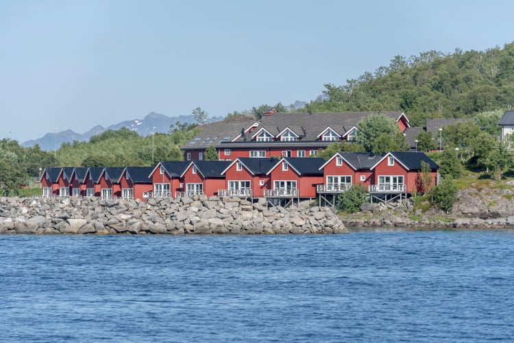 photo of view of picturesque traditional rorbuer on fjord shore, shot under bright summer light at Stokmarknes, Hadseloya, Vesteralen, Norway