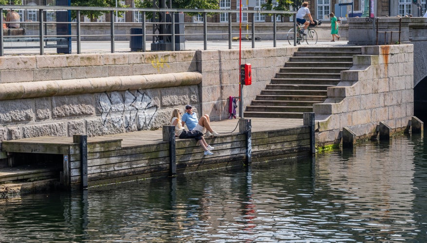 Young people enjoying the sun by Frederiksholm Canal in central Copenhagen, Denmark.jpg