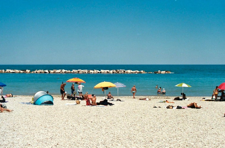 Italy. Marche. Fano. People sit on benches