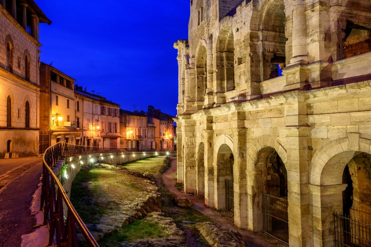 Twilight view of the Roman amphitheatre in Arles, France, with the surrounding old town and historic buildings softly lit in the background..jpg