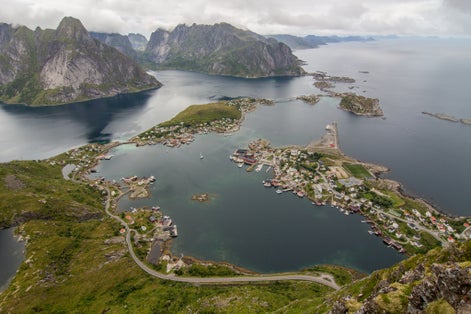 Reine village and ocean from Reinebringen mountain peak in cloudy sky. Reine, Lofoten island, Norway.