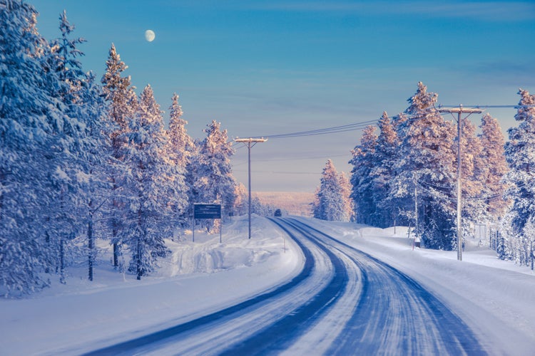 Photo of winter landscape with snow-covered road and pine trees, Ivalo.