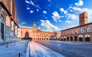 Photo of Italy Piazza Maggiore in Bologna old town tower of town hall with big clock and blue sky on background, antique buildings terracotta galleries.