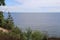 View of the Baltic Sea from the forest on the cliffs near Gdynia in Nature reserve "Kępa Redłowska". View of the beach and pier. We look through the trees.