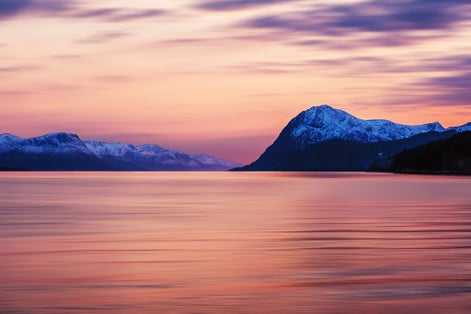 photo of view of Molde, Norway. Beautiful fjord in Norway at sunset. View of the mountains in Molde, Norway in the evening. Fjord with sea in summer, cloudy motion blurred sky and waves