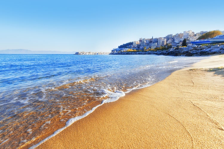 Photo of yellow sand beach against Kavala city in background. Kavala is famous summer greek resort town.