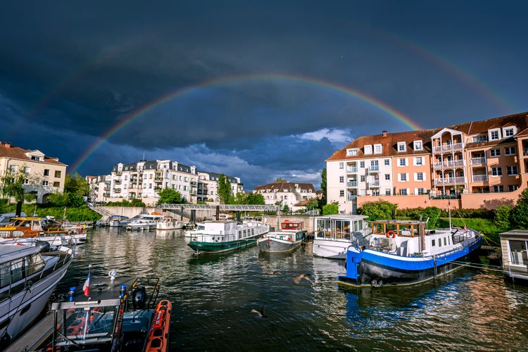 photo of view of Town of Cergy in a stormy weather with a double rainbow over Port Cergy, France.