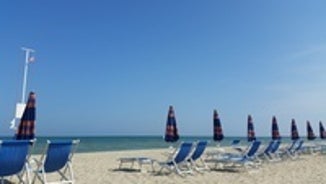 Photo of beach chairs, on a sandy, shoreline, in Giulianova, Italy.