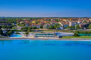 Photo of Old harbour Porto Vecchio with motor boats on turquoise water, green trees and traditional buildings in historical centre of Desenzano del Garda town, Northern Italy.