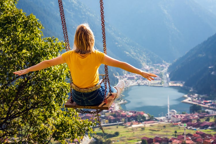 Photo of female on a swing with the view of the mountain lake Uzungol, Trabzon, Turkey.