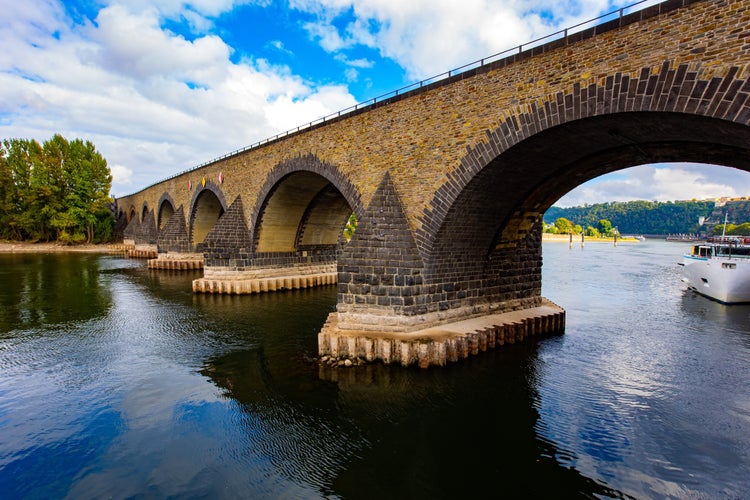 photo of view of Pleasure boat. Romantic trip to medieval Germany. Scenic Baudouin bridge over the majestic river Moselle connects the Old Town with the Lützel district. Koblenz. Cloudy warm autumn day