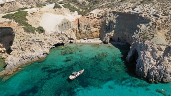 photo of view of erial drone photo of beautiful volcanic emerald paradise bay and sandy beach of Tsigrado below white rock with perlite mine, Milos island, Cyclades, Greece.
