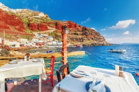 Photo of aerial view of black Perissa beach with beautiful turquoise water, sea waves and straw umbrellas, Greece.