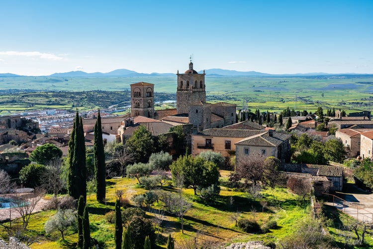 photo of Medieval churches and towers with mountainous landscape in the background in the Unesco city of Trujillo, Spain.