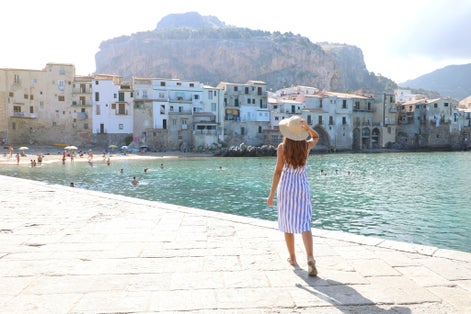 Holidays in Sicily. Back view of woman enjoying view of Cefalu old town on Sicily Island, Italy.