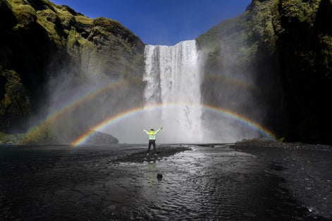 photo of tourist looking at the famous skógafoss waterfall in Iceland.