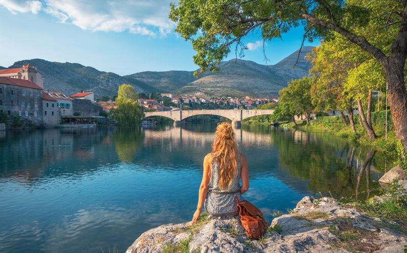 photo of Woman tourist in Trebinje looking at river and bridge in Bosnia and Herzegovina.