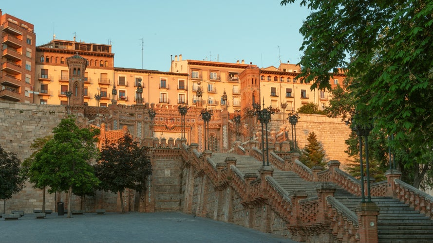 photo of view of Escalinata del Ovalo in Teruel, Spain, bathed in warm sunset light with surrounding buildings.