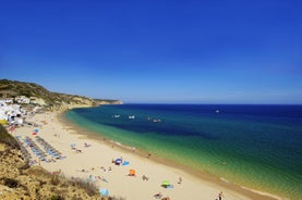 Photo of beautiful aerial view of the sandy beach surrounded by typical white houses in a sunny spring day, Carvoeiro, Lagoa, Algarve, Portugal.