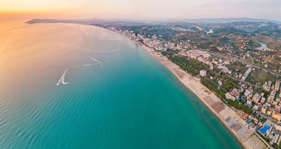 Photo of aerial view of the beautiful coastline with sandy beach of the Albanian town of Golem with the city of Durres in the background.