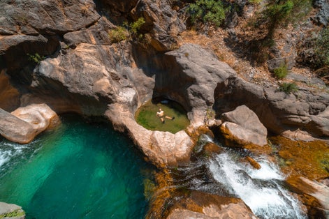 photo of a male traveler bathes in a cold mountain river. To swim at Sapadere canyon and waterfall in Summer sunny day. Antalya, Turkey.
