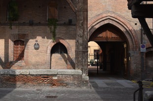 Photo of Italy Piazza Maggiore in Bologna old town tower of town hall with big clock and blue sky on background, antique buildings terracotta galleries.