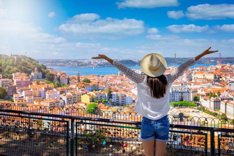 Photo of a happy tourist woman overlooks the colorful old town Alfama of Lisbon city, Portugal.