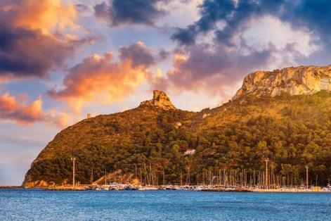 Beach of Cagliari (Poetto Sella del Diavolo) with Torre del Poetto tower and boats at sunset, Sardinia, Italy.