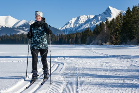 Photo of young woman cross country skiing on a snowy meadow with a view of the High Tatras-Kriváň.