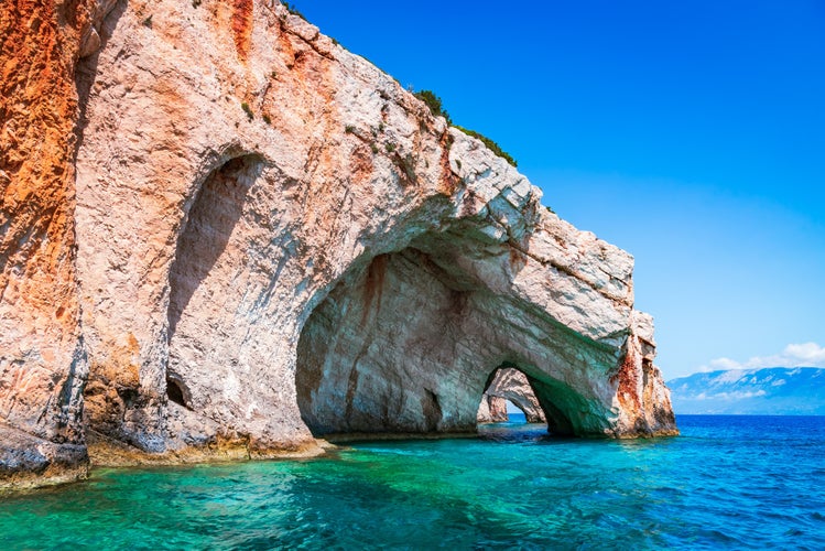 Photo of rock arches of blue Caves from sightseeing boat in blue water of Ionian Sea near Agios Nikolaos.