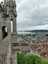 Geneva skyline cityscape, French-Swiss in Switzerland. Aerial view of Jet d'eau fountain, Lake Leman, bay and harbor from the bell tower of Saint-Pierre Cathedral. Sunny day blue sky.