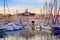 Yachts reflecting in the still water of the old Vieux Port of Marseilles beneath Cathedral of Notre Dame, France, on sunrise