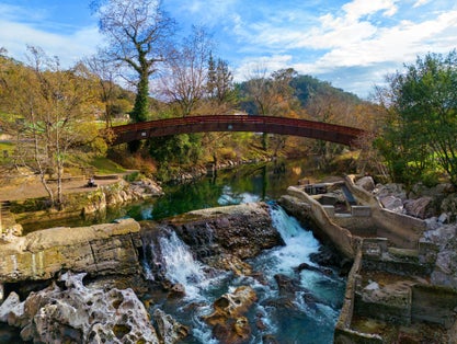 photo of a scenic view of a bridge in the woods in daylight in Puente Viesgo, Spain.