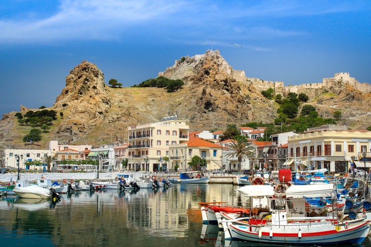 Photo of Idyllic port of little island of Limnos in the Agean Aea of Greek. Fisher boats in the front and the old castle on the hill in the background.