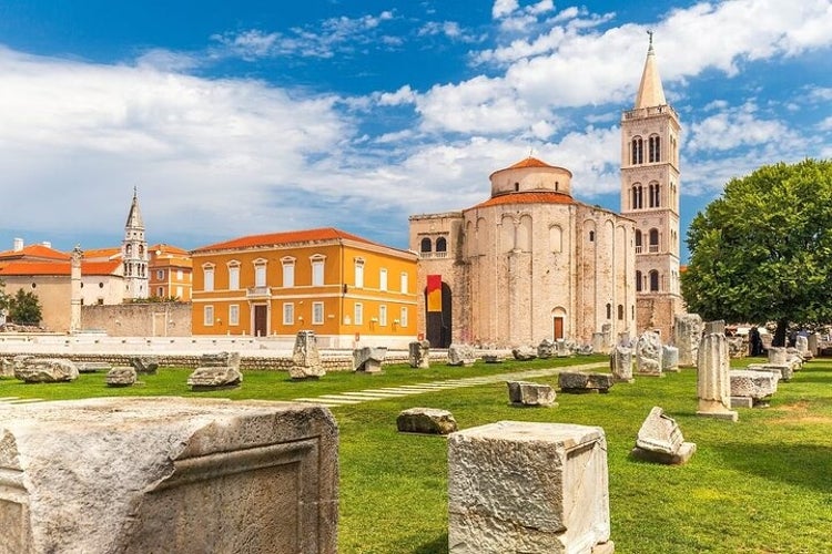 Historic Zadar with the Church of St. Donatus, bell tower, Roman ruins, vibrant buildings, and a grassy plaza under a blue sky..jpg