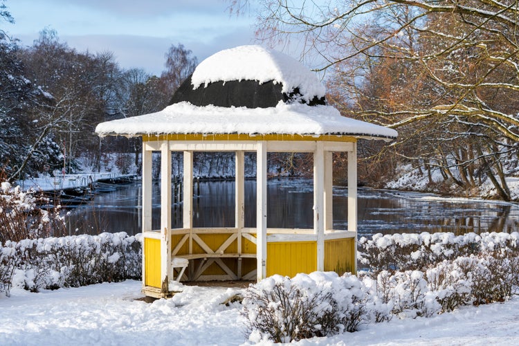 photo of view of  Traditional vintage yellow shelter during winter with river in the background. Captured in Angelholm, Sweden. Selective focus foreground.