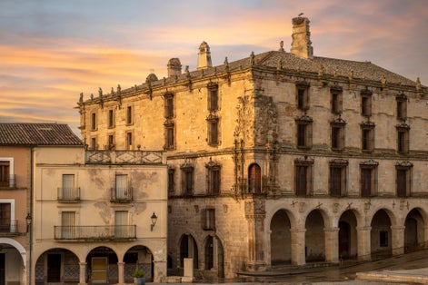 photo of the porticoed Palace of the Marquises of the Conquest in the Plaza Mayor of Trujillo, Cáceres, Spain, at dawn.