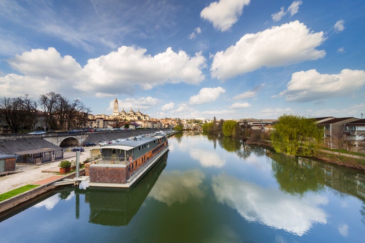 Wide sunset view of the Isle river with a barge or houseboat and the Saint Front cathedral in the background from the bridge Saint George. Perigueux.