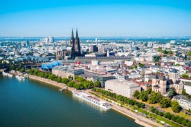 Cologne Aerial view with trains move on a bridge over the Rhine River on which cargo barges and passenger ships ply. Majestic Cologne Cathedral in the background.