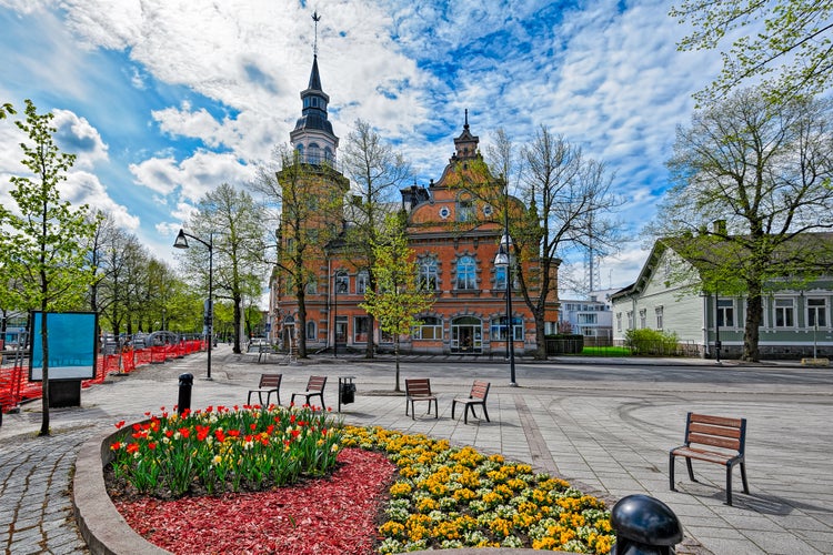 Ornate flowerbed with wooden chairs around in front of old historic buildings in the center of Rauma, Finland