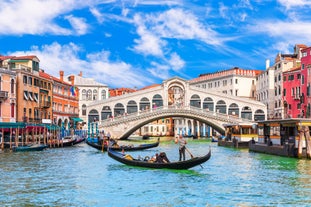 Famous buildings, gondolas and monuments by the Rialto Bridge of Venice on the Grand Canal, Italy.