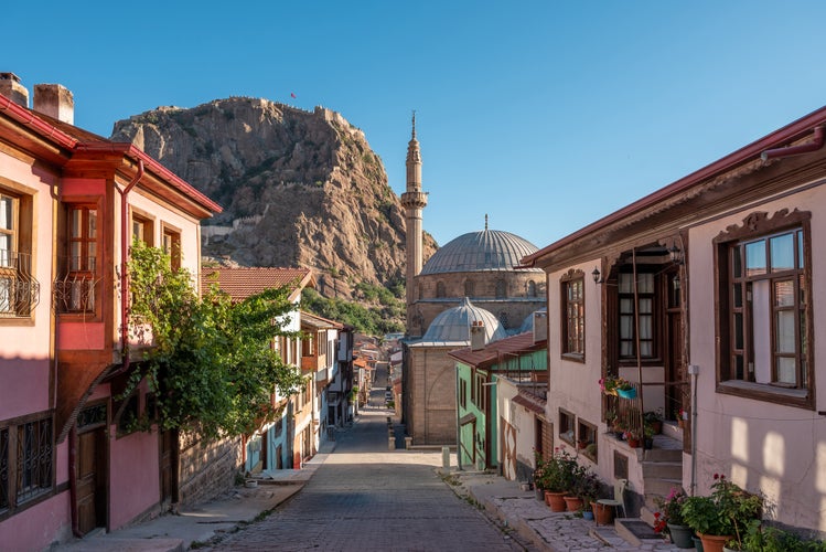 photo of traditional Turkish Ottoman houses in Afyonkarahisar Turkey. Afyon Castle on the rock and Mevlevihane Museum in front of it.