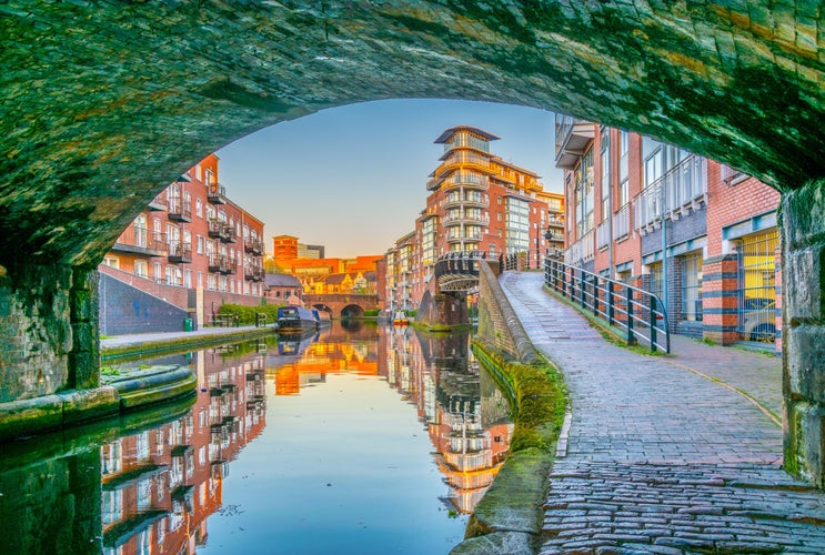 Photo of sunset view of brick buildings alongside a water channel in the central Birmingham, England.