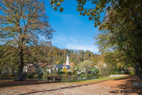 Isar riverside with autumnal trees and benches, spa town Wolfratshausen, beautiful destination in upper Bavaria