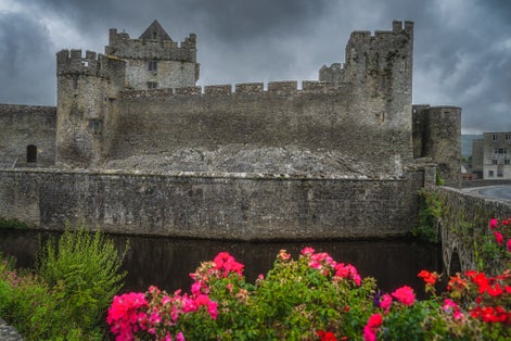 photo of 12th century Cahir castle with moat in Cahir town with dramatic, storm sky in background, County Tipperary, Ireland