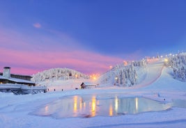 Photo of stunning sunset view over wooden huts and snow covered trees in Kuusamo, Finnish Lapland.