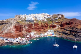 Photo of aerial view of black Perissa beach with beautiful turquoise water, sea waves and straw umbrellas, Greece.