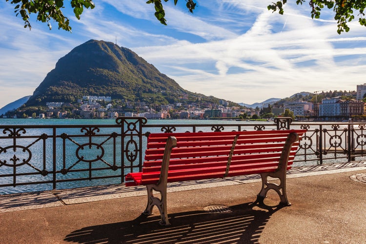 Photo of panoramic scenic view of the lake Lugano, mountains and city Lugano, Ticino canton, Switzerland. Scenic beautiful Swiss town with luxury villas.