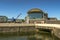 The Techniquest building in Cardiff Bay against a deep blue sky. In the foreground is one of the restored docks.